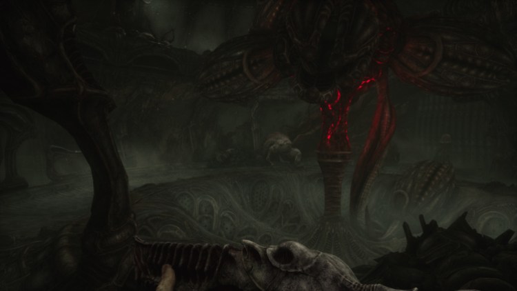 Scorn Review: a dark room with some red veins making a pillar in the center. On the other side of the pillar, a vaguely potato shaped enemy lurks